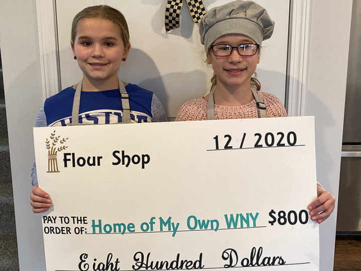 Two children holding large donation check